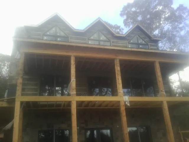 Dormers and porch framing on a large log home under construction — Roof Coating work by our crew in Tahoma