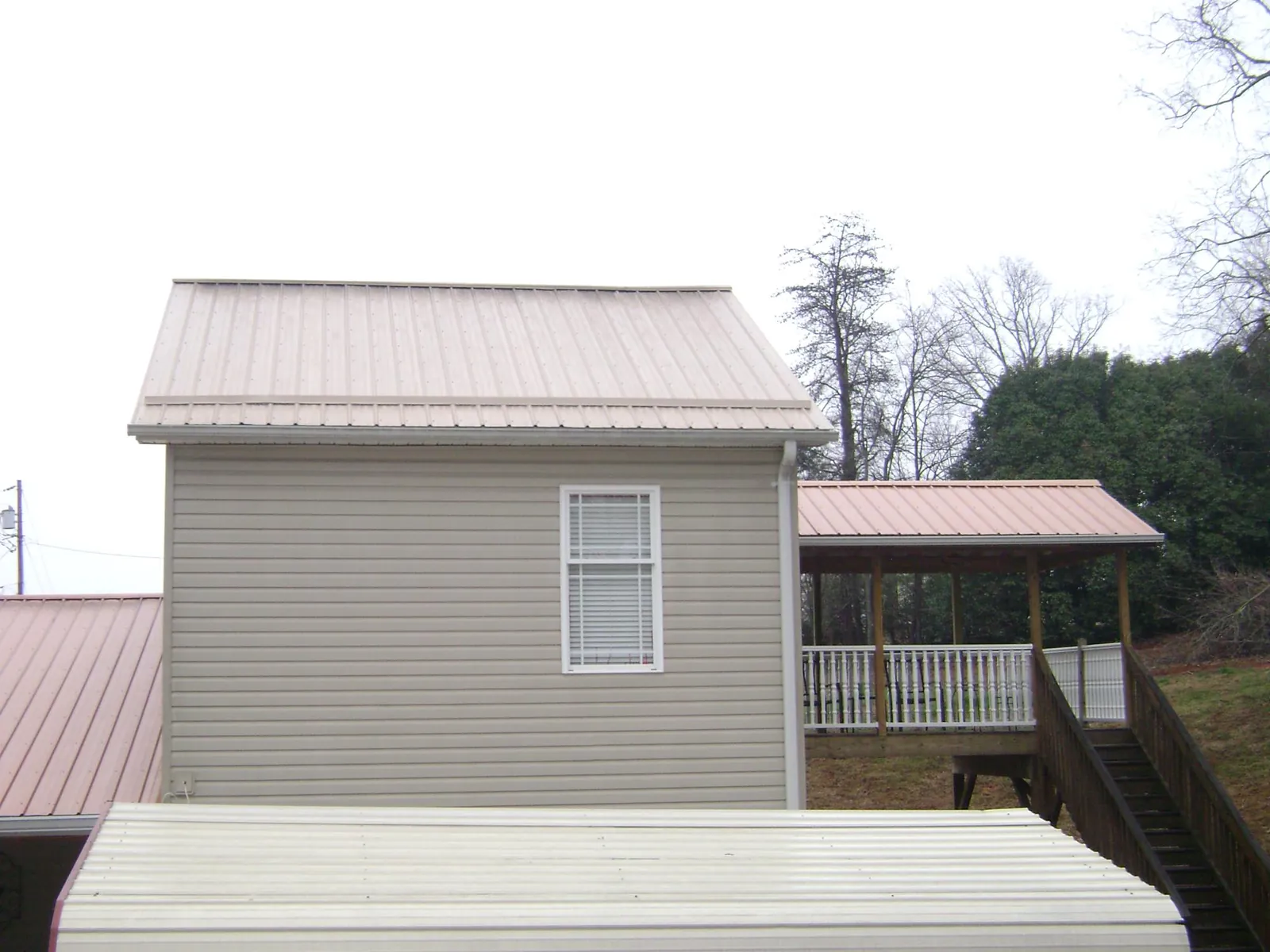 Tan metal roofs on a two story addition and attached porch, from a Roof Replacement job in Tahoma